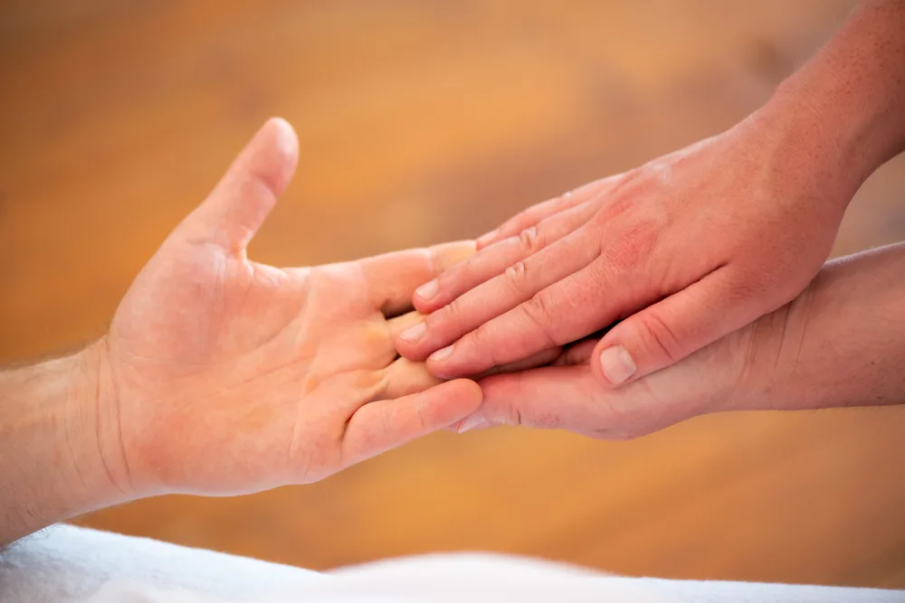 Nahaufnahme: zwei Hände massieren die Handfläche einer anderen Person